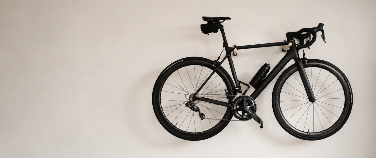 StudioVelo3D bike wall mount holding a matte black road bike against a beige wall.