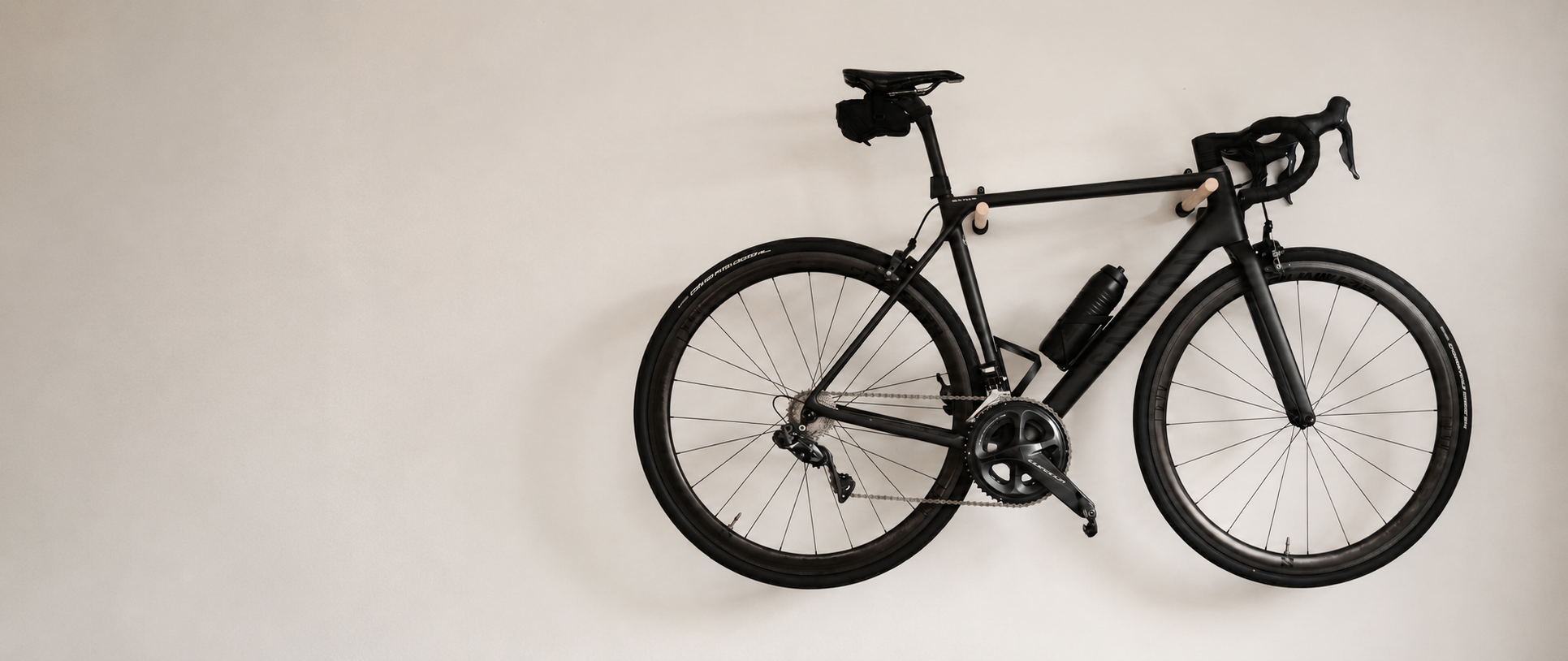 StudioVelo3D bike wall mount holding a matte black road bike against a beige wall.